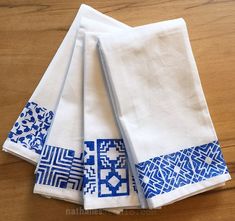 four blue and white napkins sitting on top of a wooden table