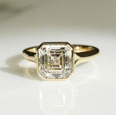 an engagement ring with a diamond in the center on a white surface, close up