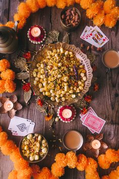 an arrangement of food on a table with candles and flowers in the middle, surrounded by other items