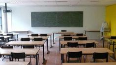 an empty classroom with desks and chalkboard