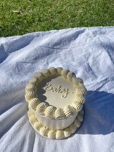 a cake sitting on top of a white sheet in the grass next to a green field