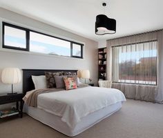 a bedroom with a large bed and two lamps on either side of the window sill