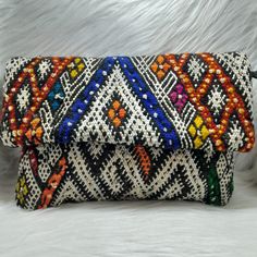 Berber Kilim Clutch Bag made in Morocco with detachable chain 11.8 x 7.4 IN Awesome clutch bag handmade from vintage Berber Kilim rugs, and coming straight from Morocco. Its geometric patterns, its tassels and its attractive colors give it a bohemian and trendy look. Sure, it will be a major piece of your outfit! Its detachable chain will allow you to carry it as a clutch bag or as a handbag. Very practical! It contains an inner pocket to hide your most precious objects. In short, it is an authentic piece and especially unique! Closing system: a flap, a zipper and 2 snaps. The imperfections that you may find on this piece guarantee its real handicraft manufacture and add to its charm. *Approximate dimensions (length x width): 30x19 cm / 11.81x7.5" IN *Length of the chain: 120 cm / 47.2" *M Bohemian Beaded Clutch For Festivals, Bohemian Beaded Pouch Clutch, Bohemian Embroidered Clutch Bag, Bohemian Multicolor Embellished Clutch, Bohemian Multicolor Embroidery Clutch, Purse Pouch, Crossbody Shoulder Bag, Shoulder Bag Women, Wallets For Women