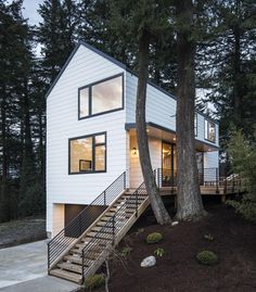 a white house with stairs leading up to the front door and trees in the background