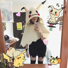 a woman taking a selfie in front of a mirror with pokemon costumes around her