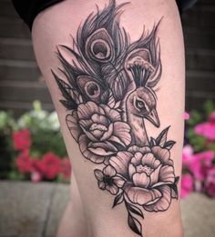 a woman's thigh with a peacock and flowers on it