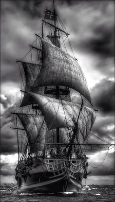 an old sailing ship in the middle of the ocean with dark clouds above it and water below