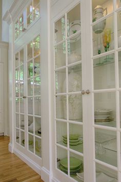 a white china cabinet with glass doors and plates