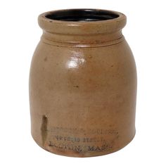 a brown ceramic jar with an inscription on the front and bottom, is shown against a white background