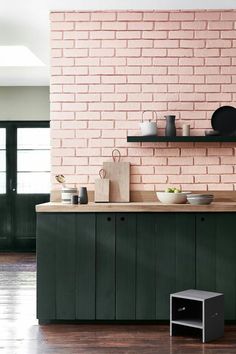 an image of a kitchen with pink brick walls and dark green cupboards on the counter