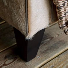 an upholstered bench with wood and fur on it's backrests