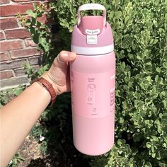 a hand holding a pink insulated water bottle