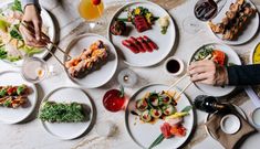 people are eating sushi and chopsticks at a table with plates on it