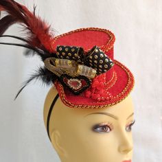 Red velour mini top hat Fascinator decorated with red and gold trims, ribbons, red coque tail feathers, and embellishments.  It features a red velour heart with a crystal embellishment, and gold/black trim edges.  Great accessory for a Mad Hatter or Alice in Wonderland party. Can also be worn at the races or any costume party. It holds to the head with a black elastic band. Place the elastic at the back of your head under your hairline. Handmade in Australia. Laura Lucci's Collection Red Adjustable Hat For Costume Party, Adjustable Red Hat For Costume Party, Red Christmas Costume Hat, Red Christmas Costume Hat And Headpiece, Red Costume Hat, Red Party Hat With Round Crown, Red Adjustable Hat, Red Adjustable Hat With Round Crown, Red Adjustable Round Crown Hat