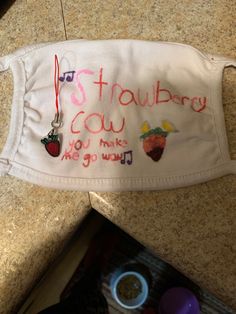 a white face mask with embroidered words and pictures on it sitting on top of a counter