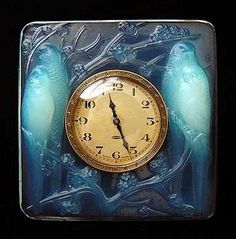 a clock with two blue birds sitting on it's sides in front of a black background