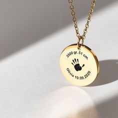 a gold necklace with a hand print on the disc that says, my first year is over 10 00