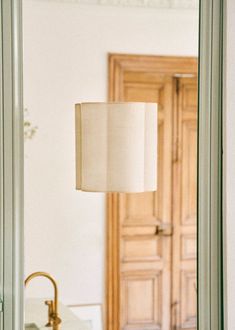 a bathroom mirror with a lamp on top of it next to a sink and door