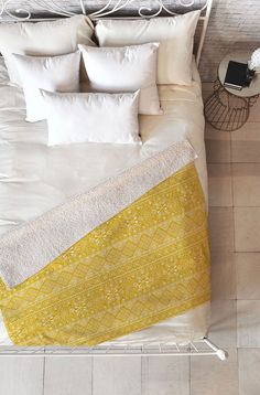 an overhead view of a bed with pillows and blankets on it, next to a phone