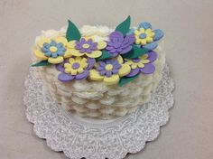 a decorated cake on a doily with purple and yellow flowers sitting on top of it