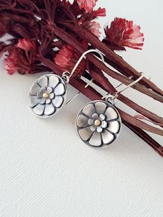 A single large flower blooms, with a tiny flower layered inside; a 14k gold ball fused in the center adds a touch of rich color. These simple dangle earrings feature just one large blossom, cut and carved by hand from sterling silver. The silver is oxidized and given a brushed finish to add depth and dimension to the e Flying Crow, Simple Dangle Earrings, Wild Garden, Metalwork Jewelry, Tiny Flowers, Rings Simple, Flower Ring, Large Flowers, Flower Earrings