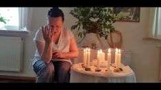 a woman sitting in front of a cake with lit candles