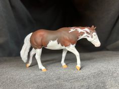 a toy horse with white and brown paint on it's body