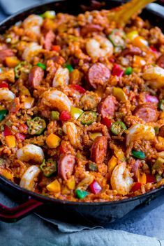 a skillet filled with shrimp, rice and vegetables on top of a blue towel