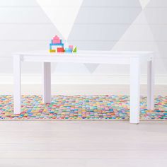 a white table with toys on top of it in front of a colorful rug and wall