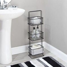 a white sink sitting next to a black and white towel rack on a bathroom floor