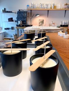 several black buckets with wooden spoons sticking out of them on a counter top