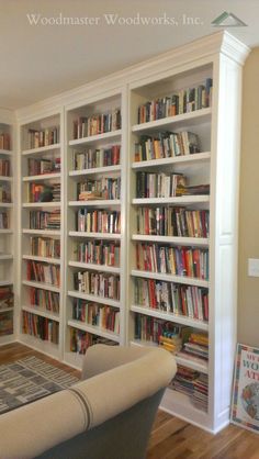 a living room filled with lots of white bookshelves next to a couch in front of a window