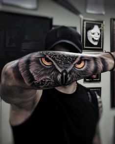 a man with an owl tattoo on his arm is holding out his hand to the camera