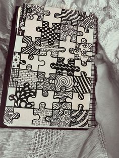 an open notebook sitting on top of a white sheet covered in black and white artwork