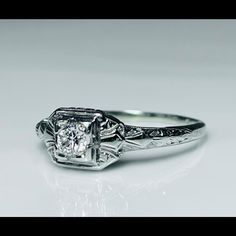 a white gold engagement ring with an old - fashioned diamond center and filigrees