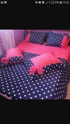 a bed with black and white polka dot sheets, red pillow cases and pink pillows