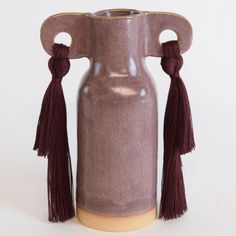 a brown vase with tassels on it