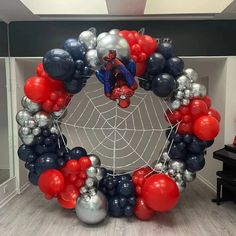 a spiderman balloon wreath with red, white and blue balloons hanging from it's center