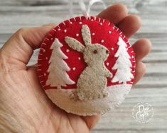 a hand holding a red and white ornament with a bunny in the center