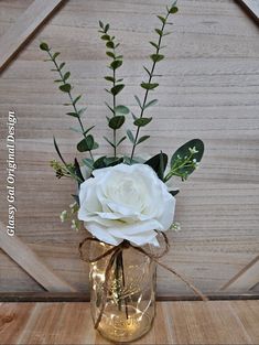 a white rose in a mason jar with greenery