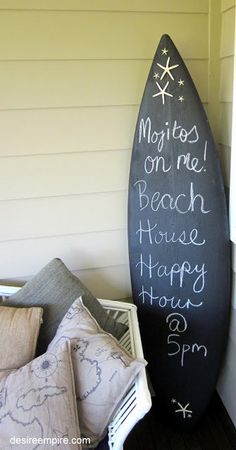 a black surfboard sitting on top of a wooden floor next to pillows and blankets