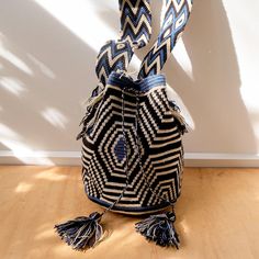 a black and white bag sitting on top of a wooden floor next to a wall