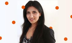 a woman standing in front of a white wall with orange polka dots on the wall