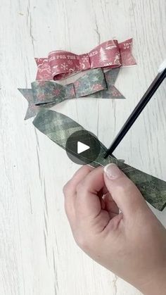 someone is holding scissors and cutting out some paper bows on a white wooden table with pink flowers