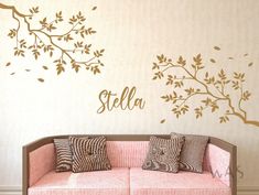 a living room with a pink couch and tree wall decal