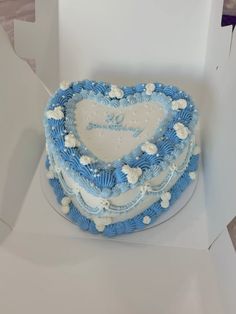 a blue and white heart shaped cake in a box