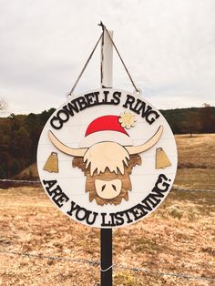 a sign that says cowbell's ring are you listening? on the side of a fence