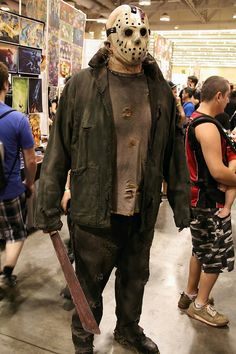 a group of people standing around in a convention hall wearing costumes and holding skateboards