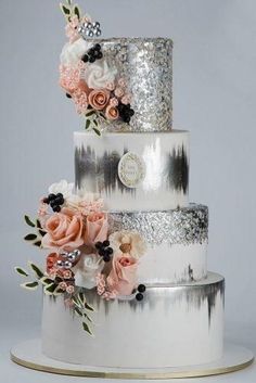 a three tiered wedding cake with flowers on the top and silver sequins