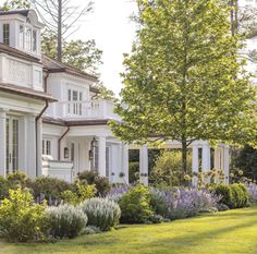 a large white house surrounded by trees and flowers